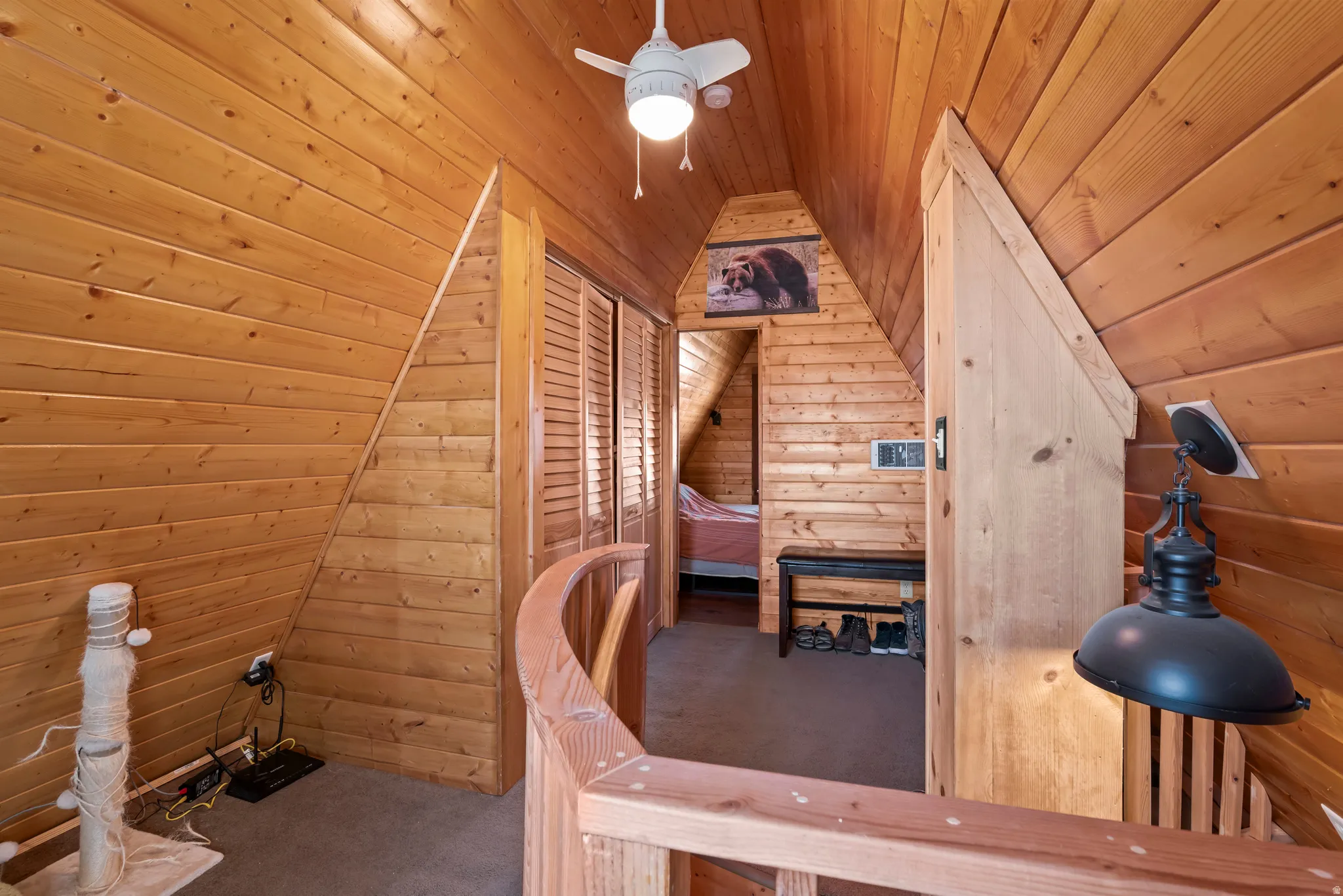 Carpeted bedroom with wood walls, wooden ceiling, and ceiling fan