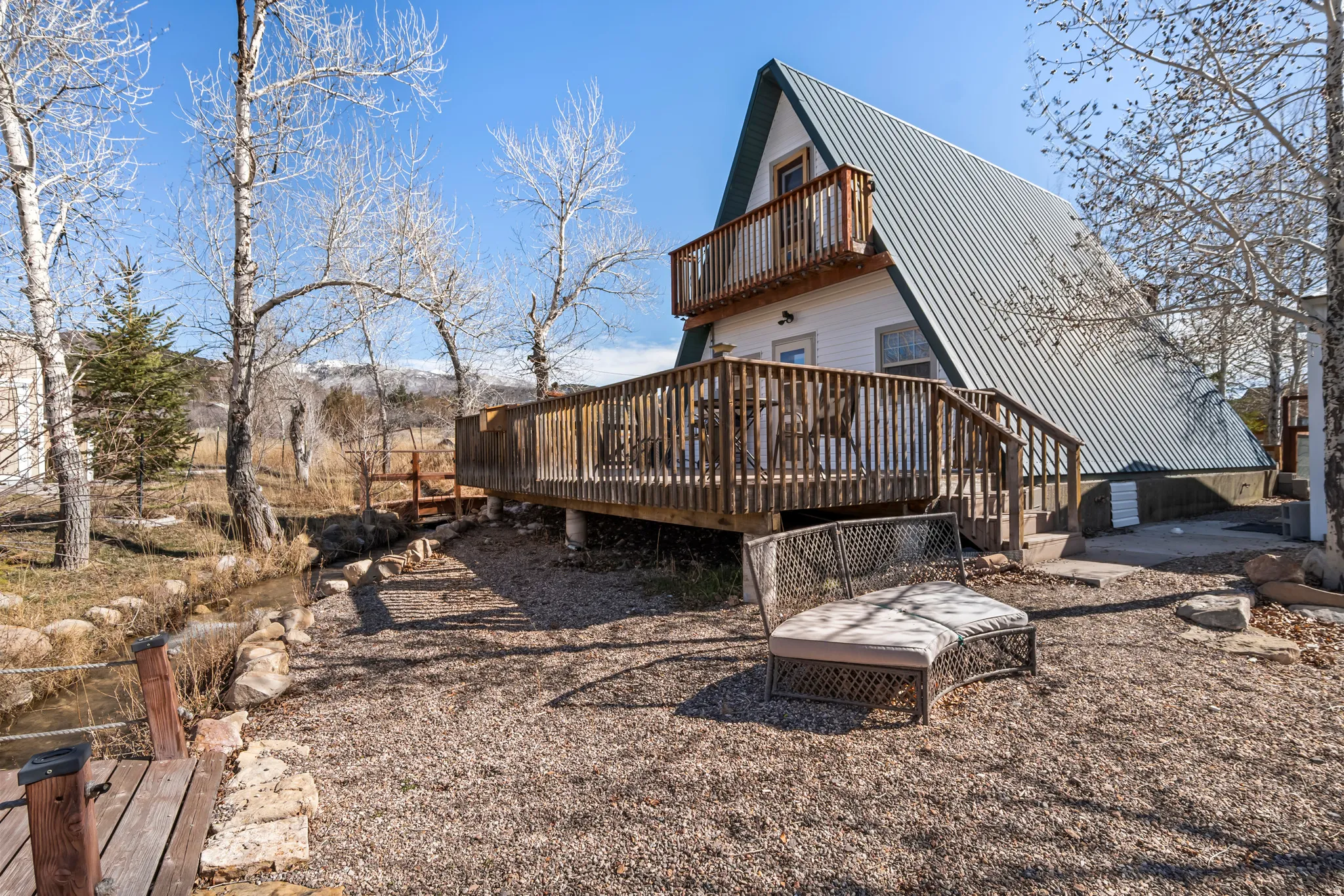 Rear view of property featuring a deck, a metal roof, and a balcony