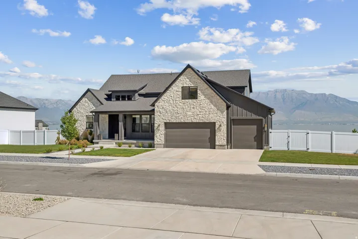 Modern farmhouse style home with a mountain view, stone siding, a gate, and board and batten siding