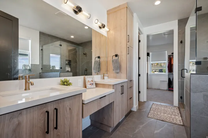 Full bathroom with two vanities, a shower stall, and recessed lighting