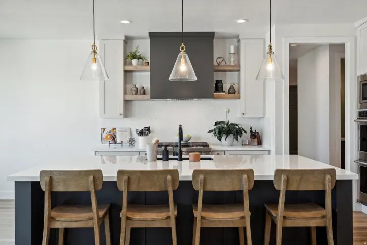 Kitchen with a breakfast bar, extractor fan, a center island with sink, wood finished floors, and dual tone cabinetry