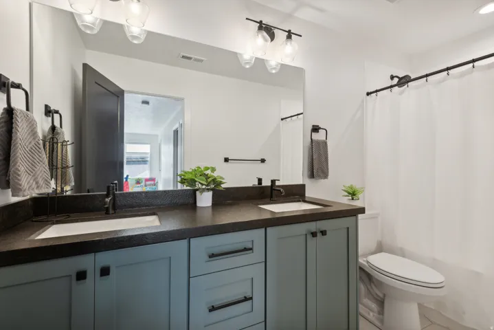 Bathroom with double vanity, shower / tub combo with curtain, and tile patterned flooring