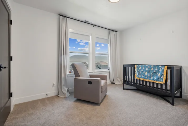 Bedroom featuring a nursery area and light carpet
