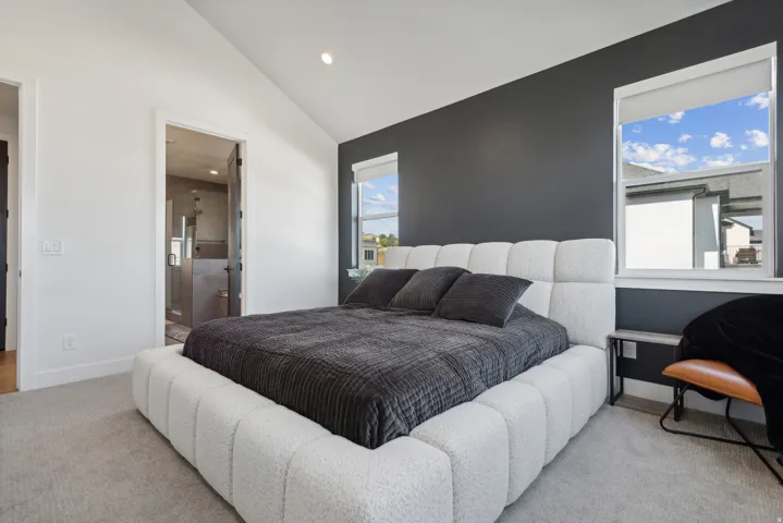 Bedroom with recessed lighting, ensuite bath, lofted ceiling, and light carpet