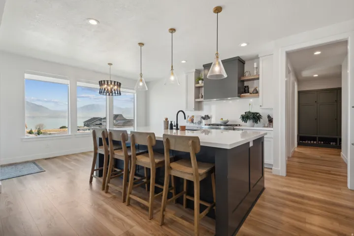 Kitchen with a kitchen breakfast bar, light wood-style floors, dual tone cabinetry, open shelves, and a kitchen island with sink