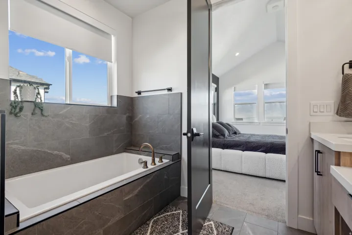 Bathroom featuring vanity, ensuite bathroom, a garden tub, plenty of natural light, and vaulted ceiling