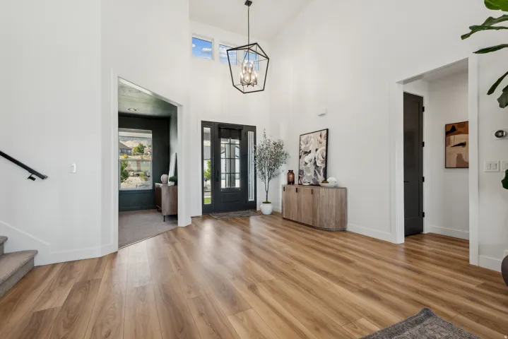 Foyer entrance featuring light wood-style floors, hanging lights, and a high ceiling
