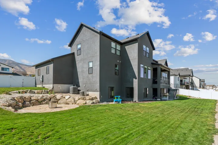 Rear view of property with a fenced backyard, a gate, a balcony, stucco siding, and a patio