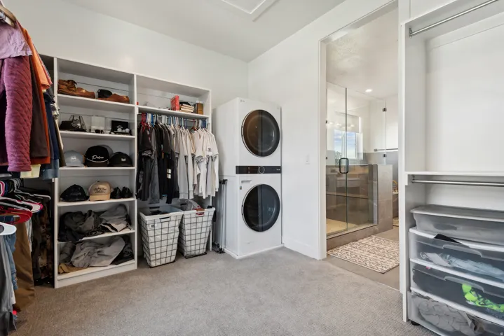Walk in closet featuring stacked washer and clothes dryer and light colored carpet
