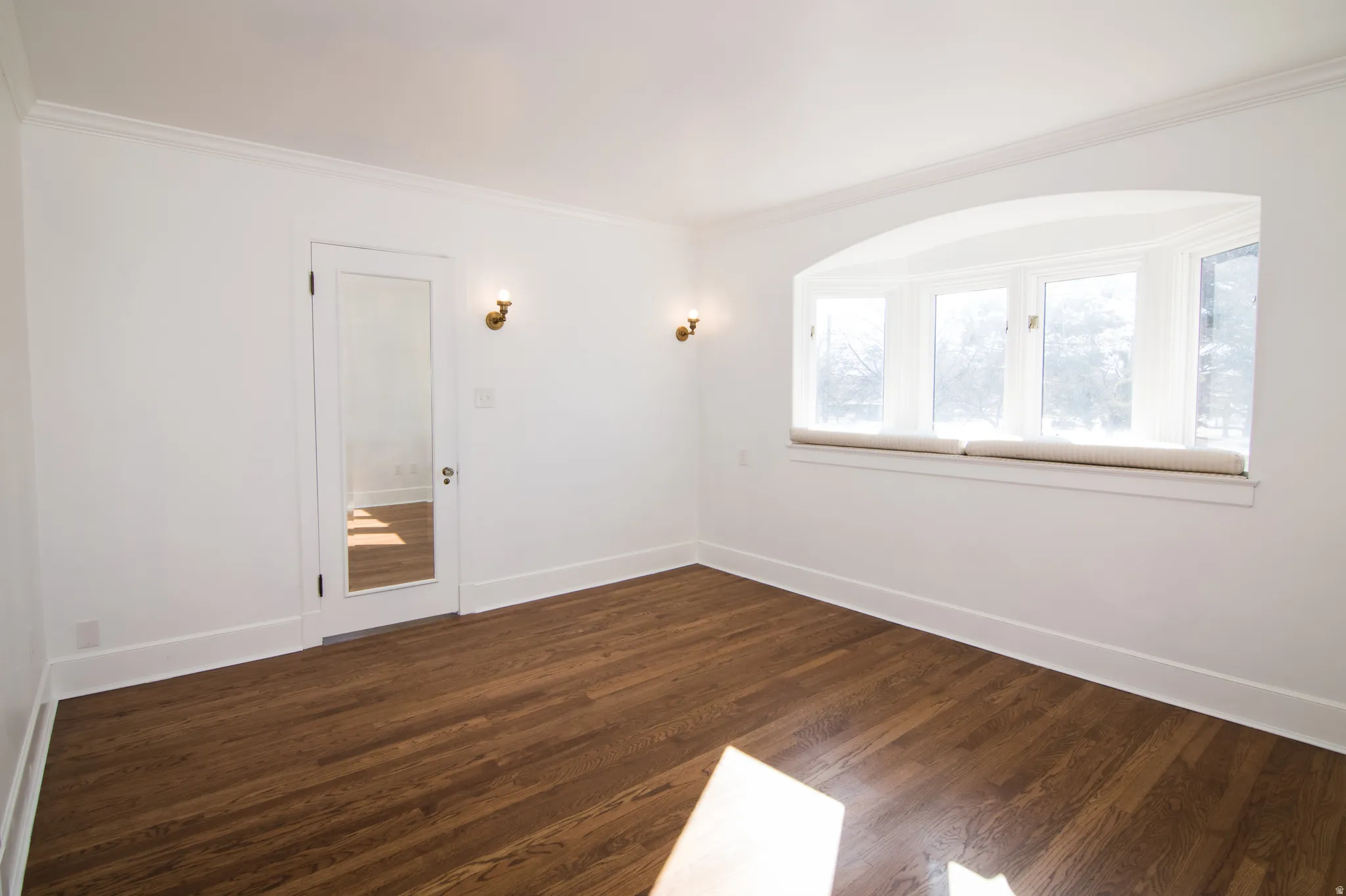 Empty room featuring dark wood-style flooring and crown molding