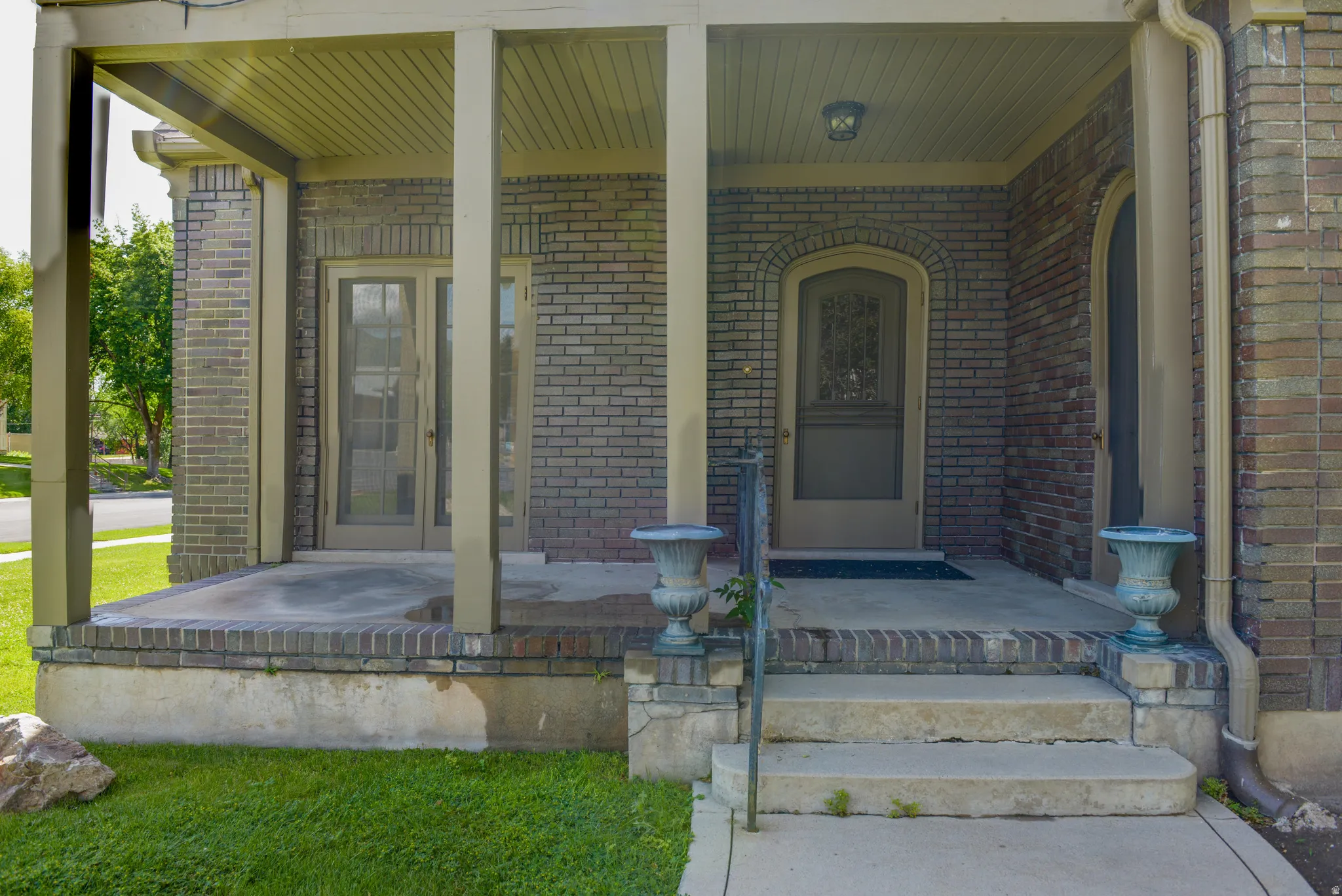 Entrance to property with a porch and brick siding