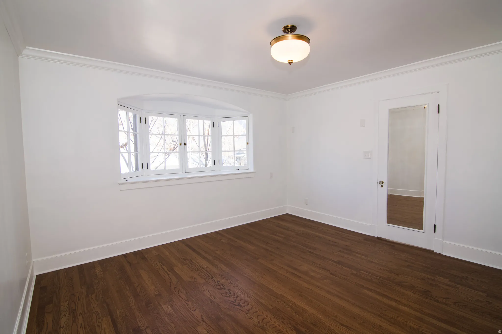 Empty room with dark wood finished floors and crown molding