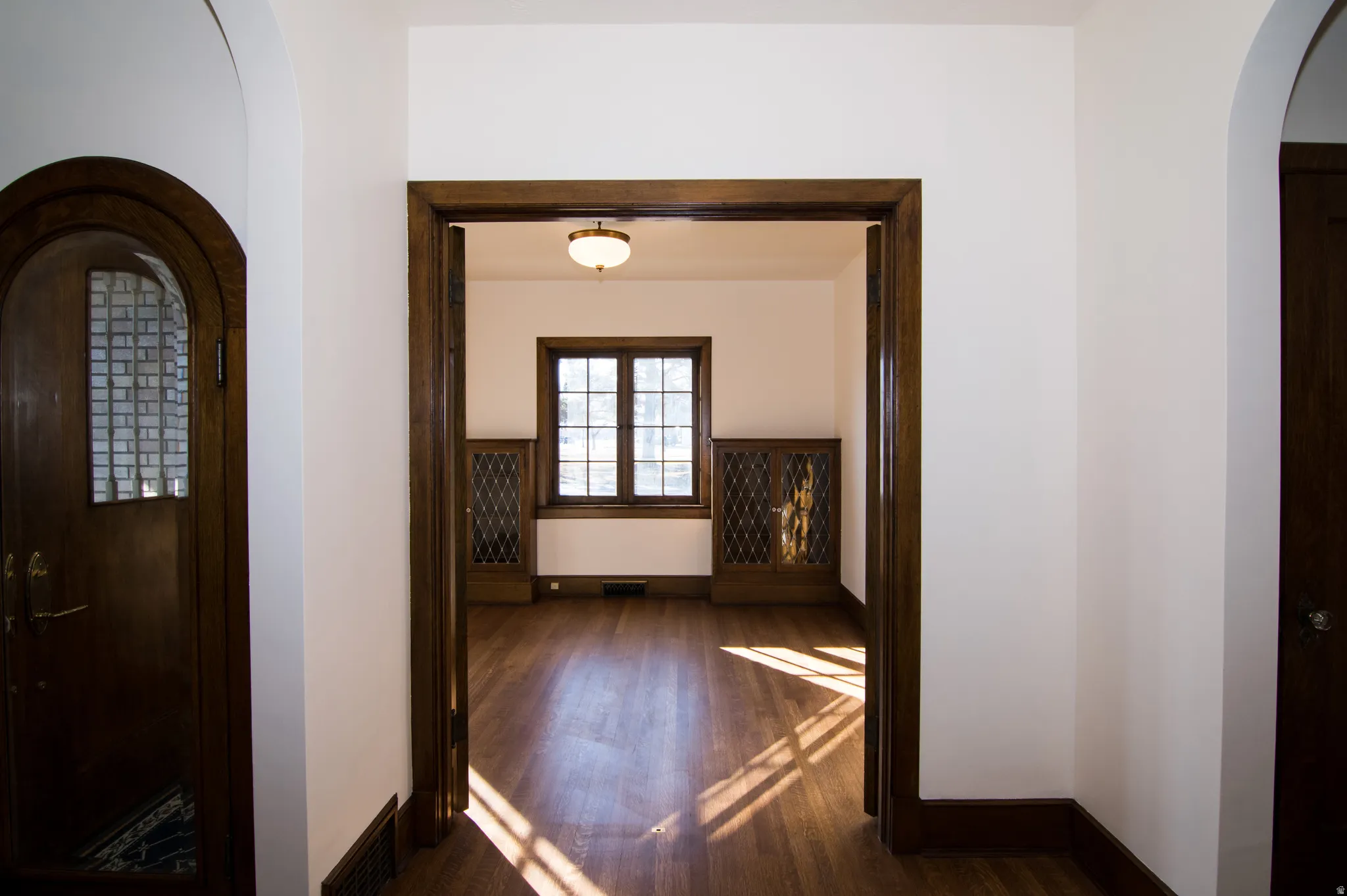 Corridor with arched walkways and dark wood-type flooring