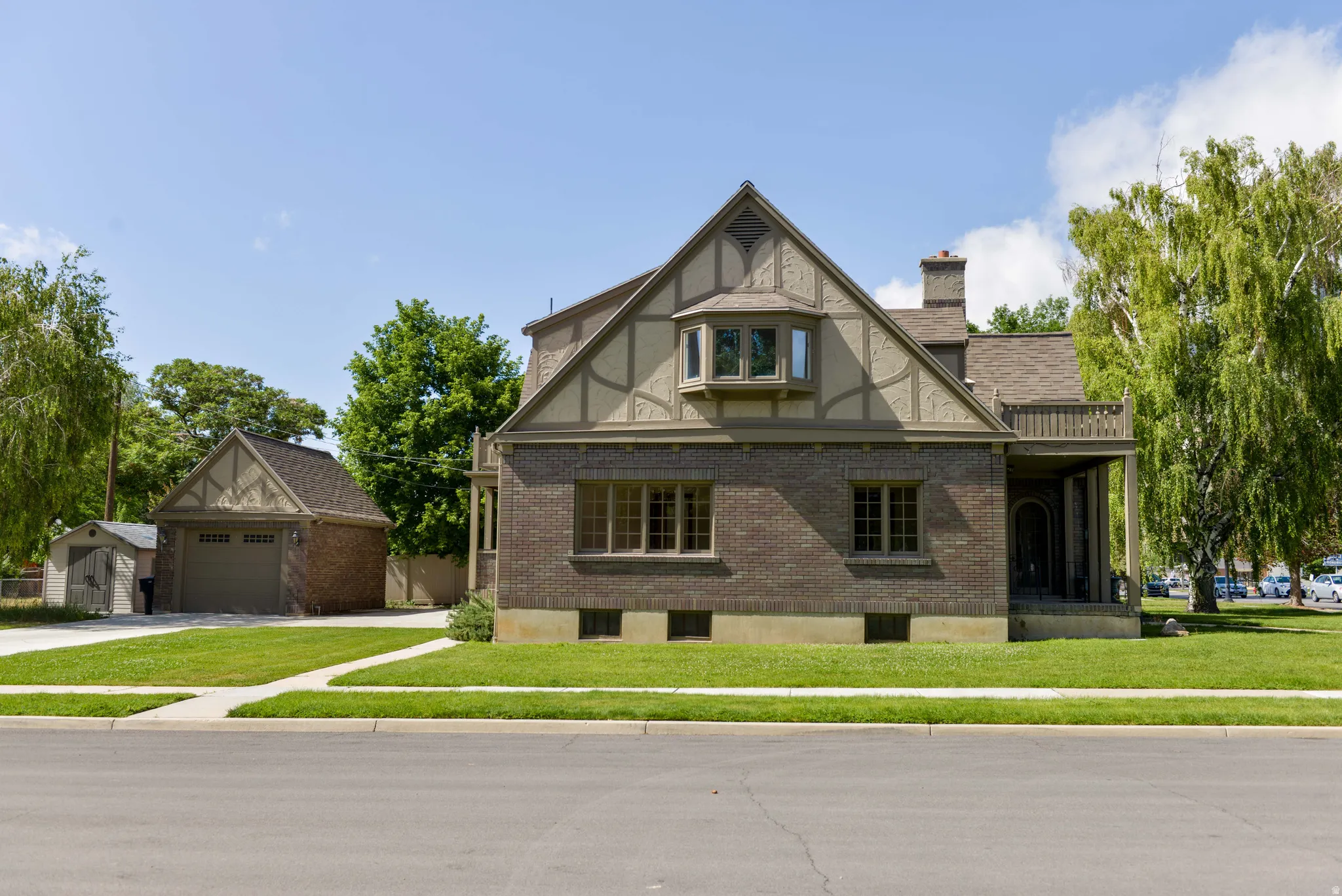 Tudor home with brick siding, an outbuilding, a front lawn, and a chimney