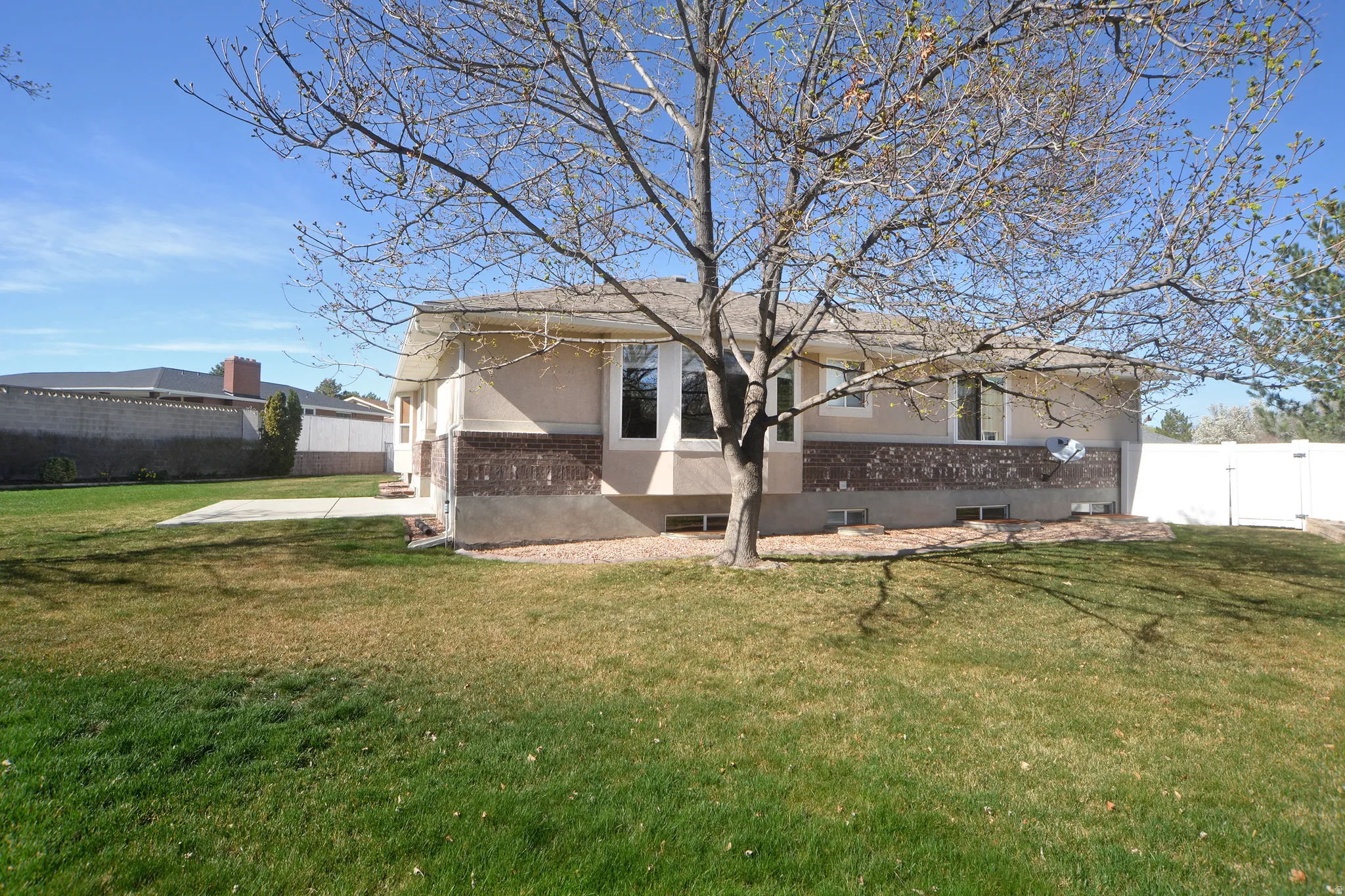 Rear view of property with brick siding, a gate, and stucco siding
