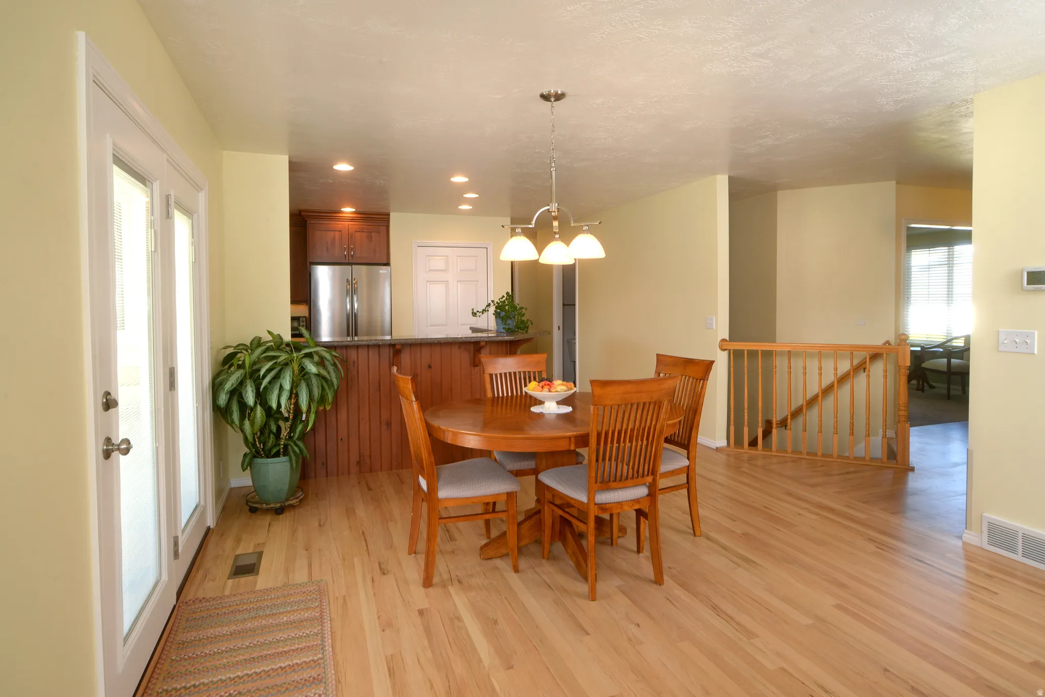 Dining room featuring healthy amount of natural light, light wood-style floors, and suspended lighting