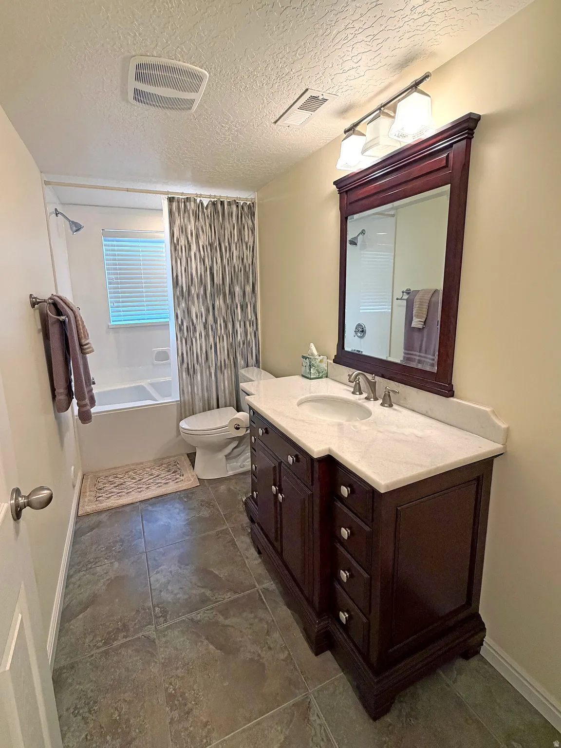 Bathroom featuring vanity, a textured ceiling, and shower / bath combo