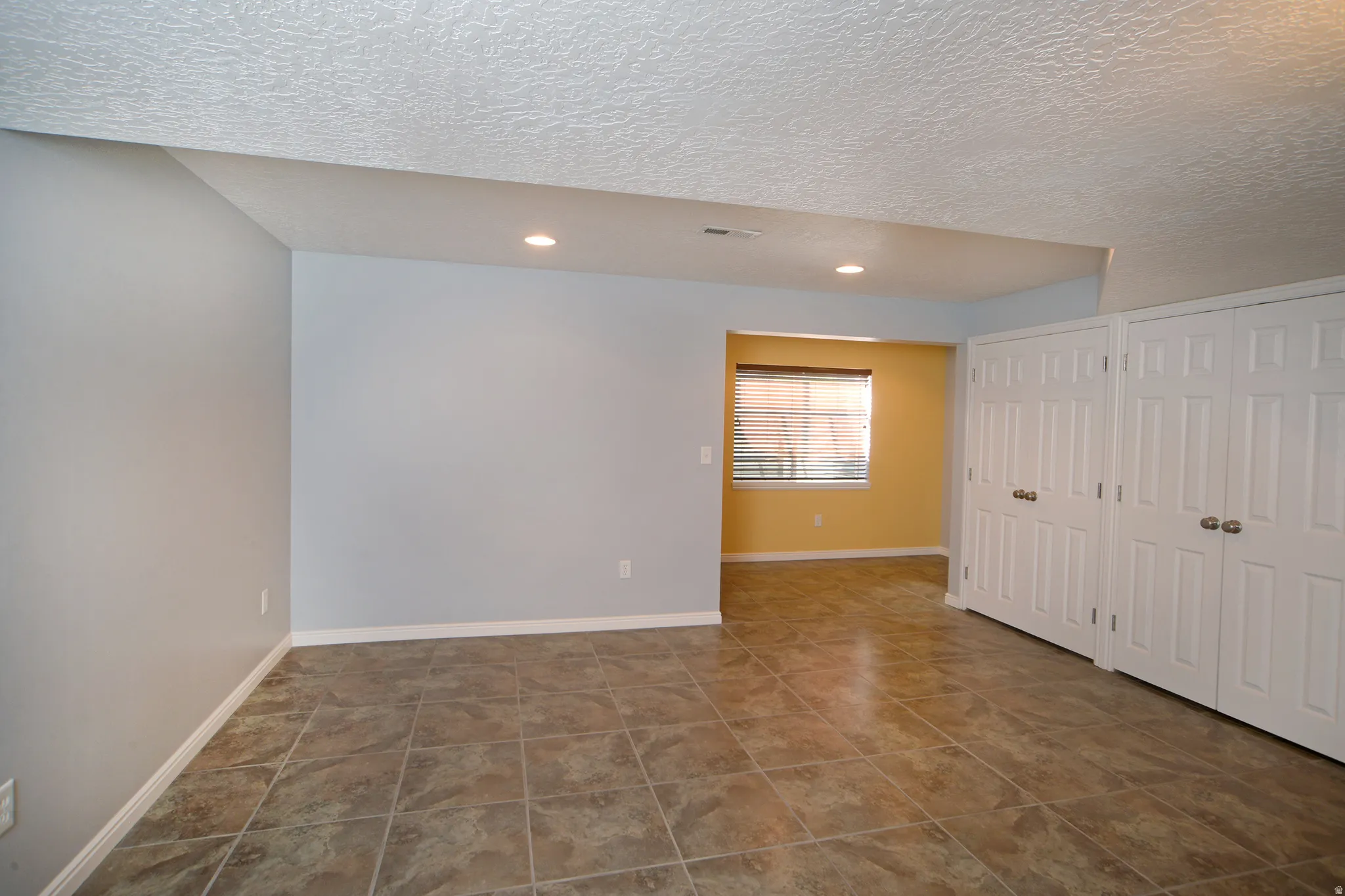 Unfurnished bedroom featuring multiple closets, a textured ceiling, and recessed lighting