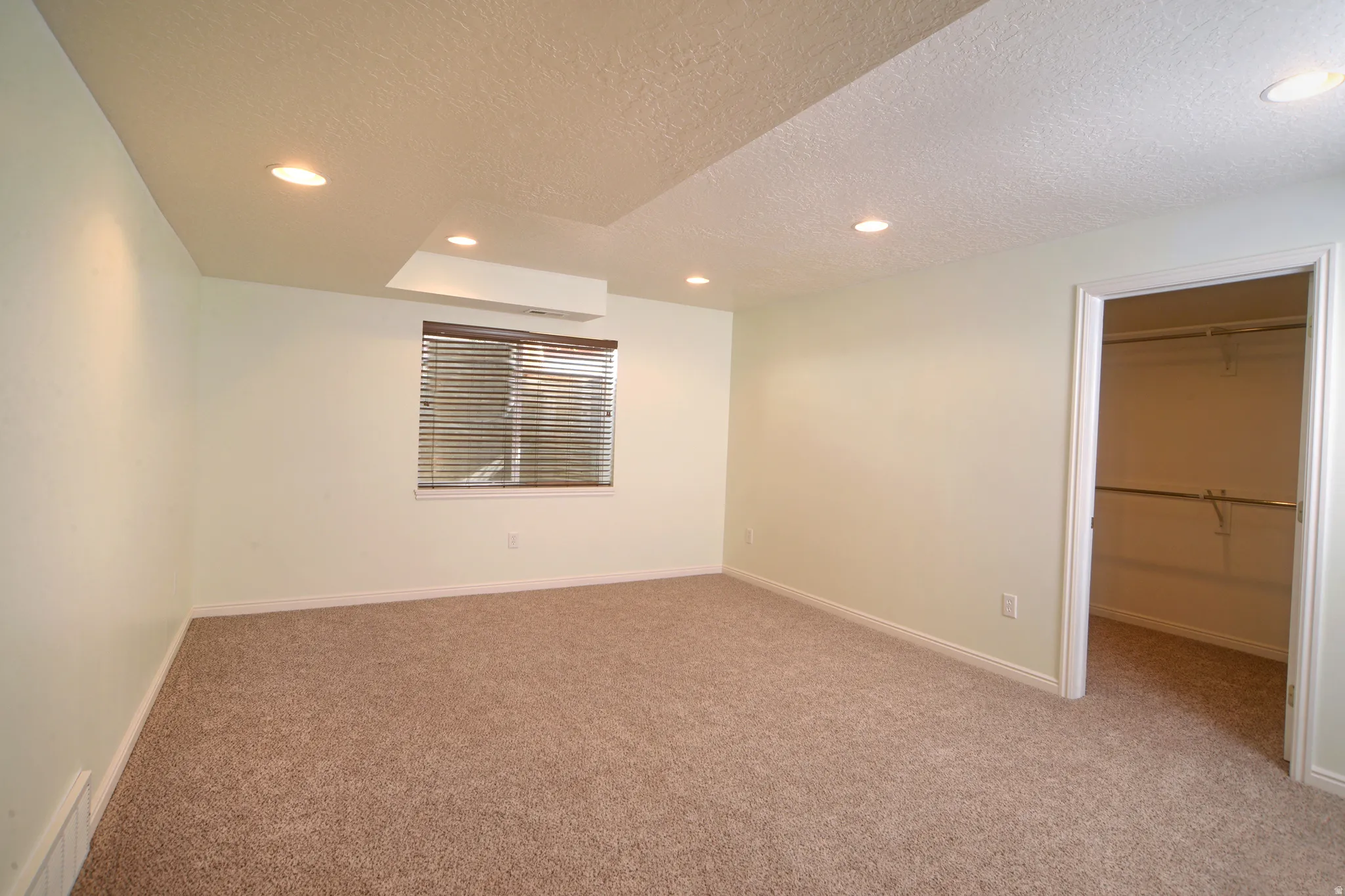 Unfurnished bedroom featuring a textured ceiling, a spacious closet, carpet flooring, and recessed lighting