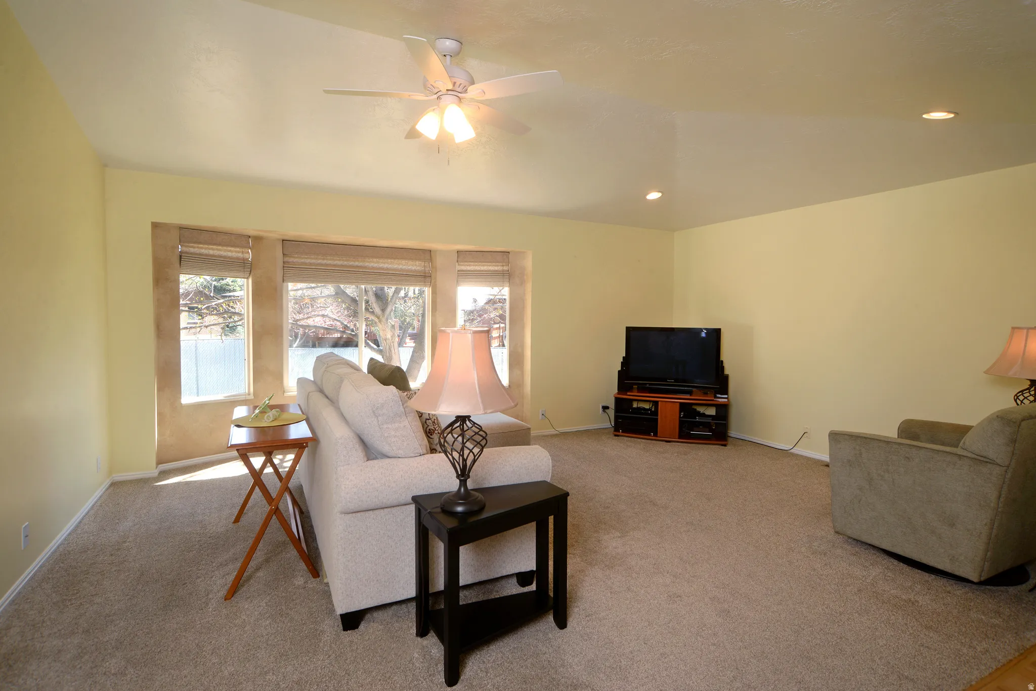 Carpeted living area featuring ceiling fan and recessed lighting