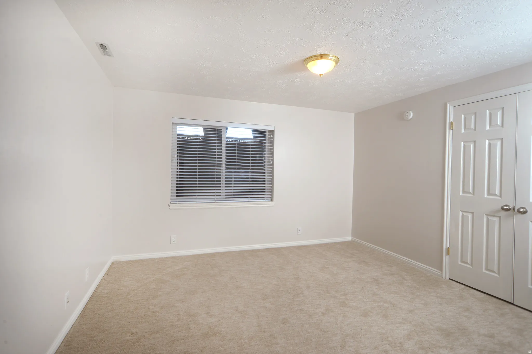 Spare room featuring light carpet and a textured ceiling