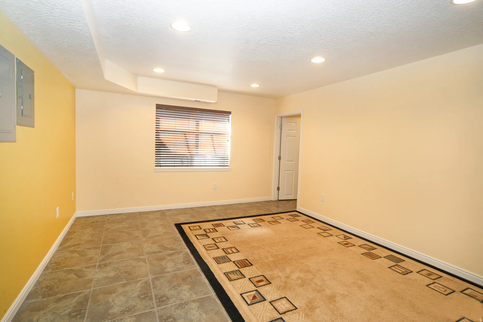 Spare room featuring recessed lighting, electric panel, a textured ceiling, and light tile patterned flooring