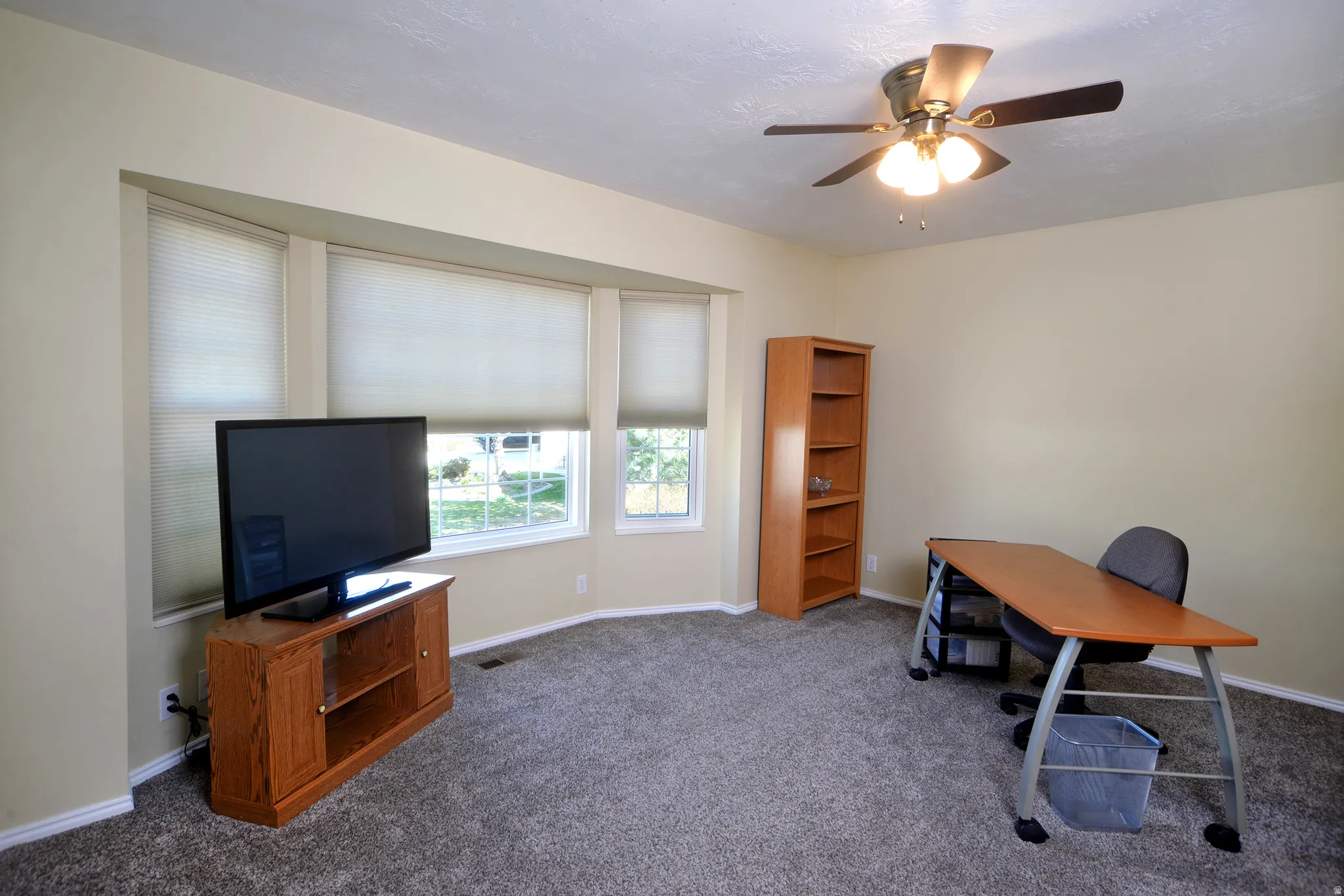 Home office with a ceiling fan and dark colored carpet
