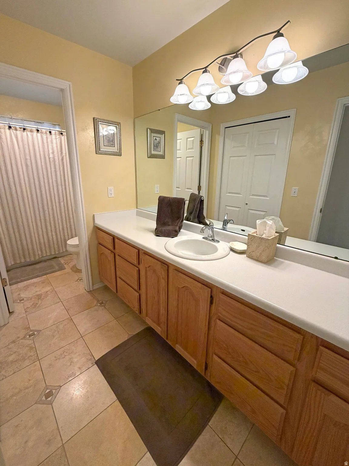 Full bathroom featuring vanity, light tile patterned floors, and curtained shower