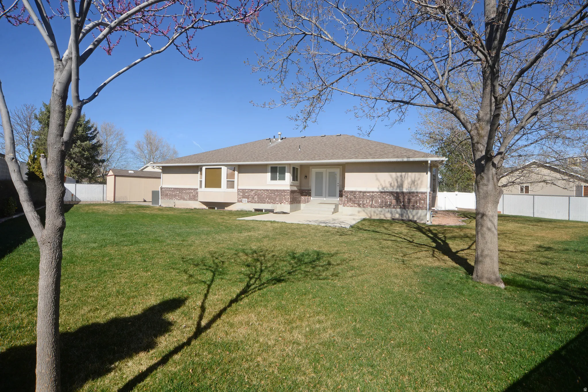 Back of house featuring brick siding, stucco siding, and a shingled roof