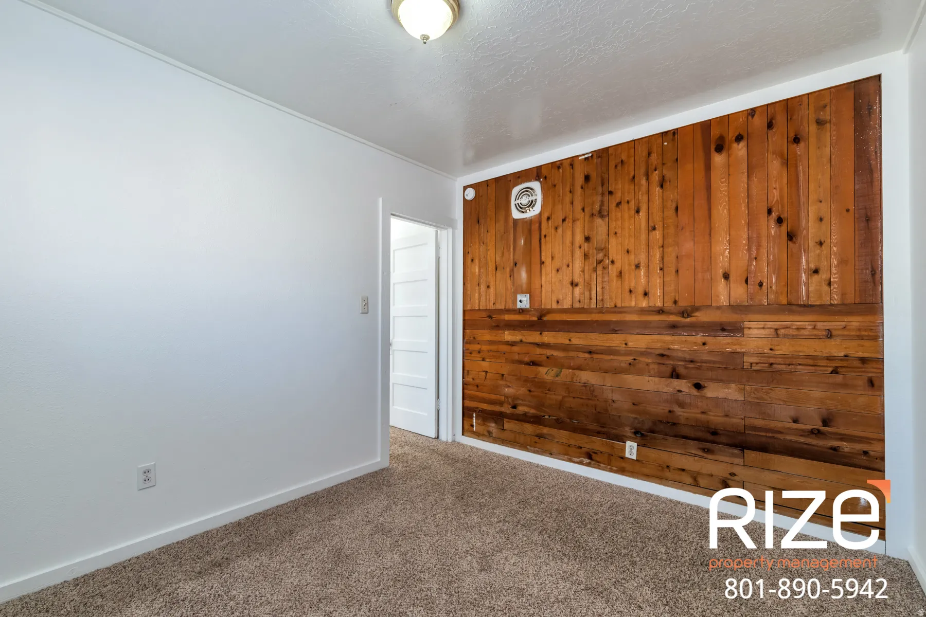 Carpeted empty room featuring wood walls and a textured ceiling