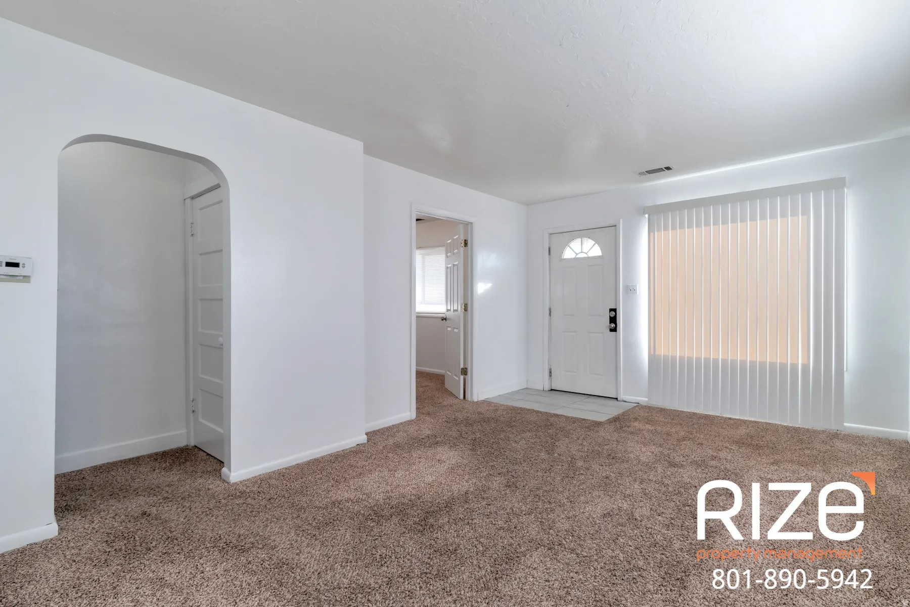 Entrance foyer with arched walkways and light colored carpet