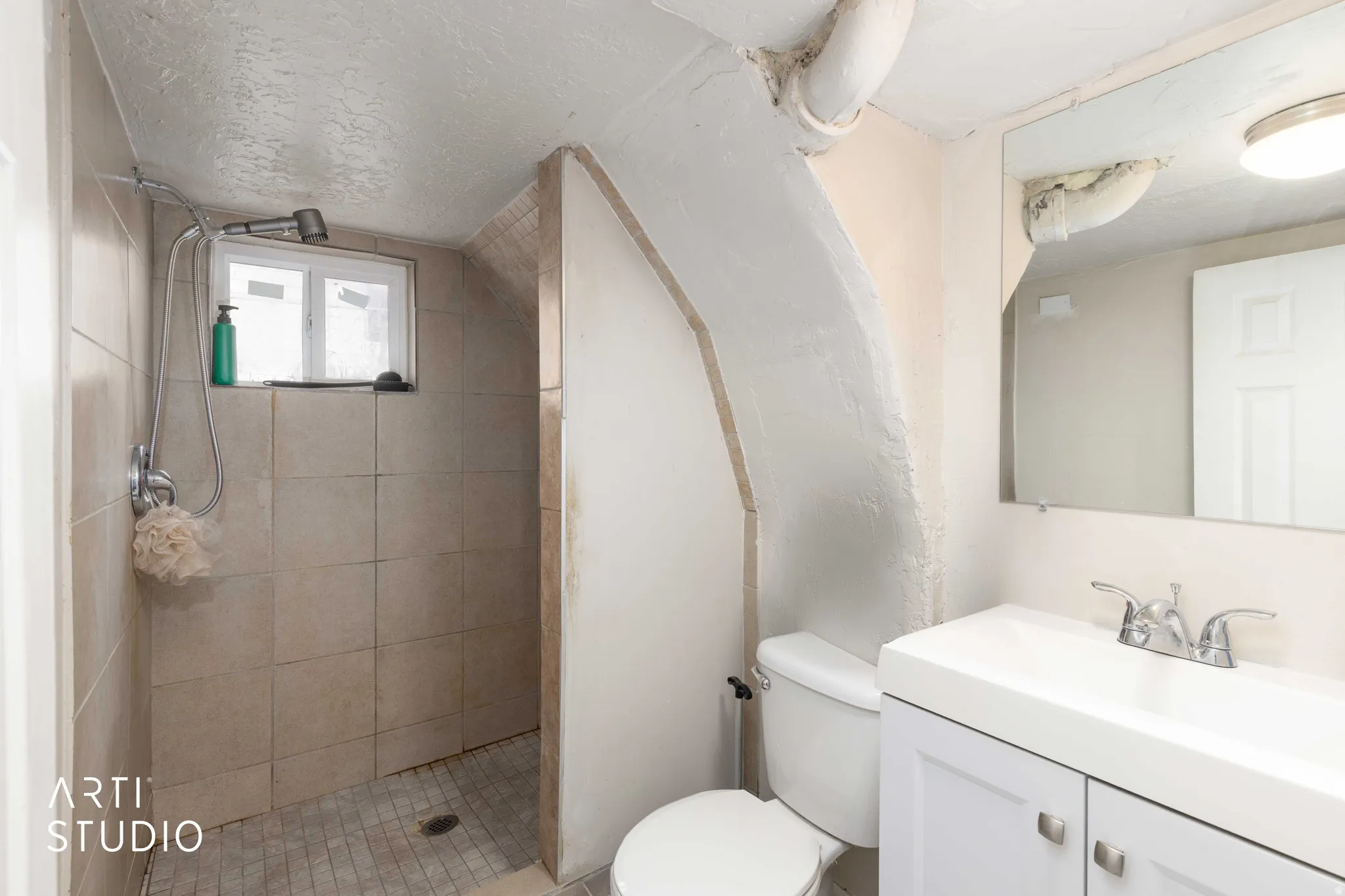 Bathroom featuring vanity, a textured ceiling, and tiled shower