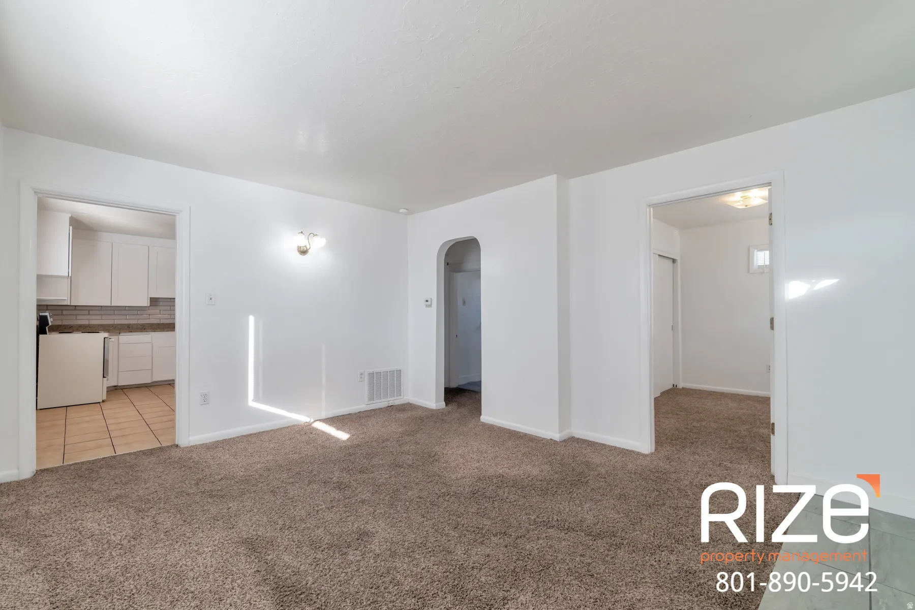 Spare room featuring arched walkways, light carpet, and light tile patterned floors