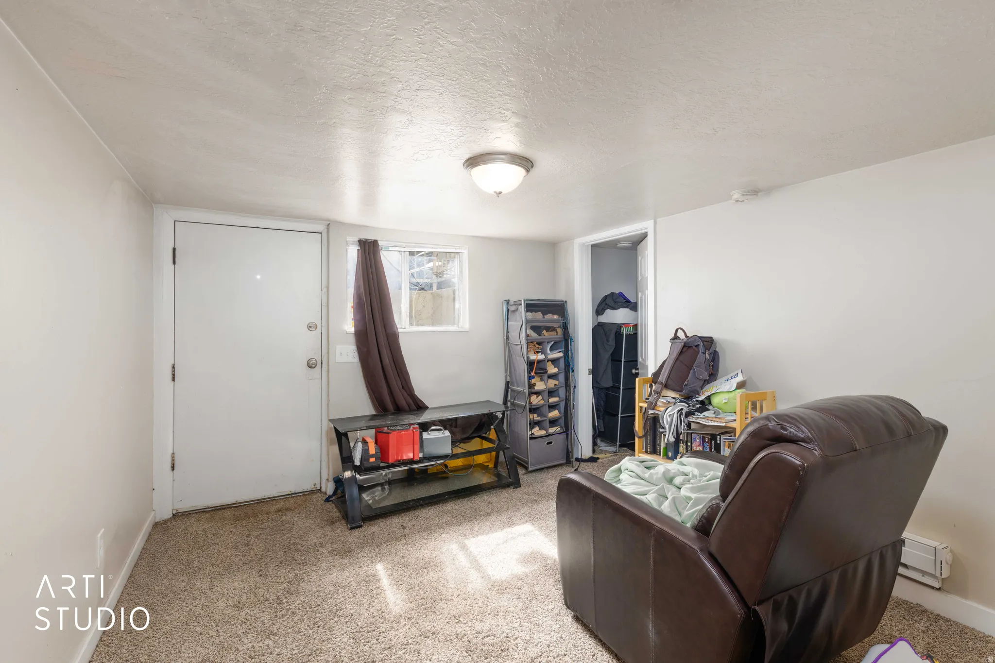 Sitting room with a textured ceiling, a baseboard heating unit, and light carpet