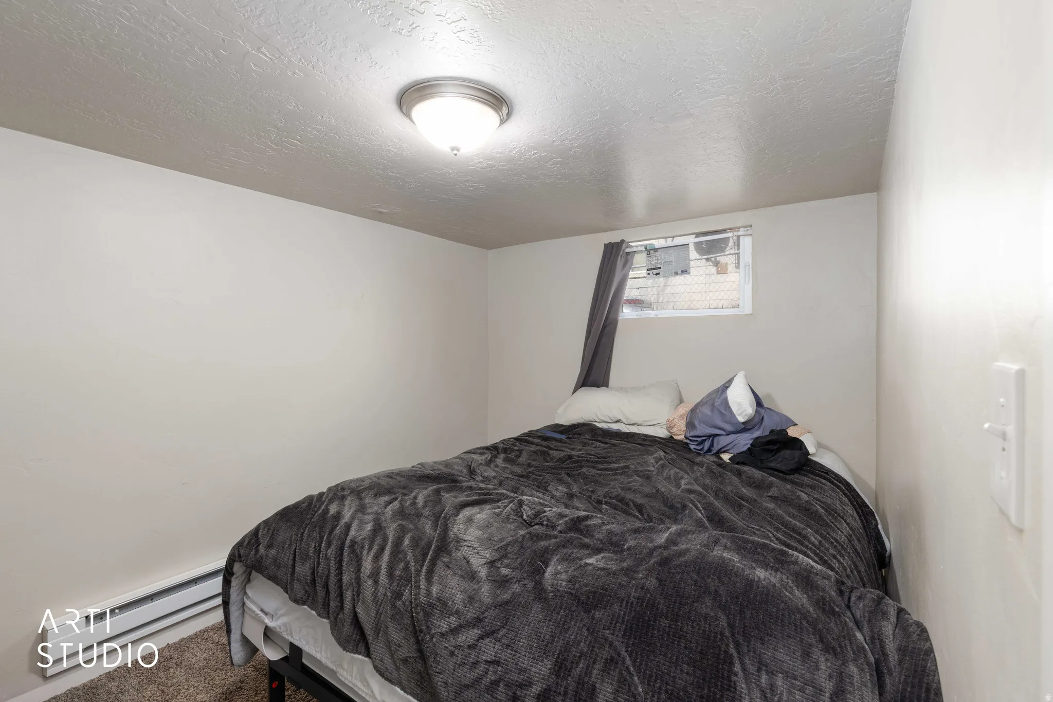 Carpeted bedroom with a textured ceiling and baseboard heating