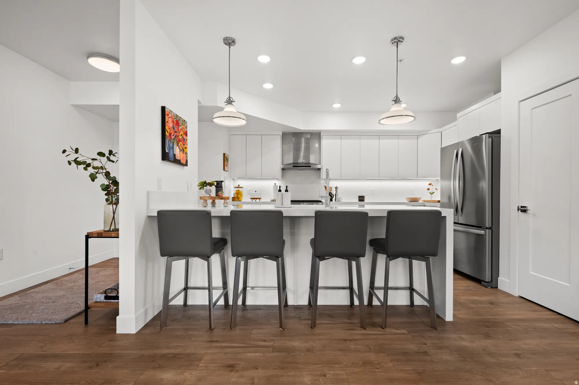 Kitchen featuring a peninsula, a breakfast bar, white cabinetry, and dark wood-style flooring