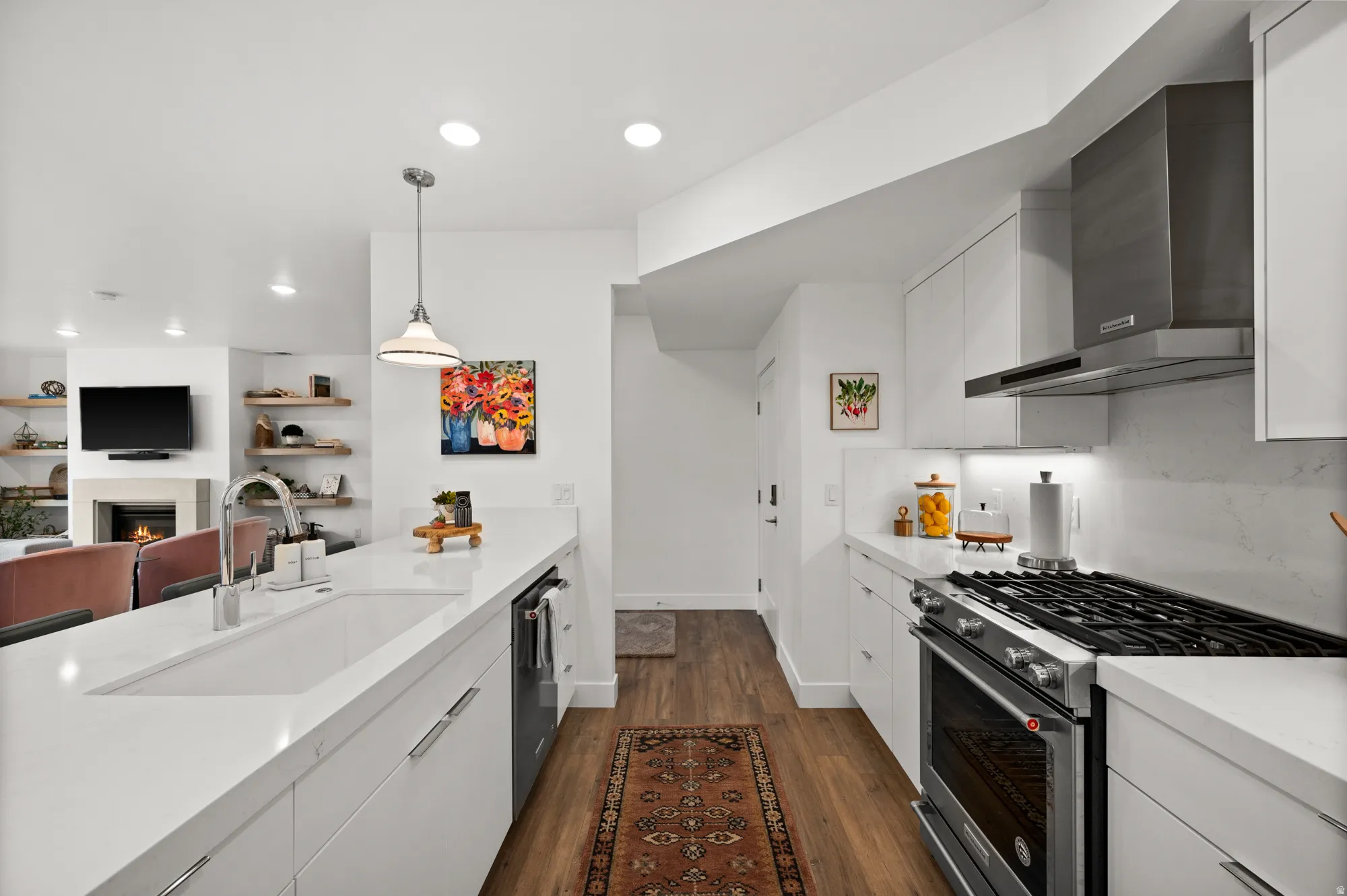 Kitchen with stainless steel appliances, white cabinetry, light stone counters, dark wood-type flooring, and pendant lighting