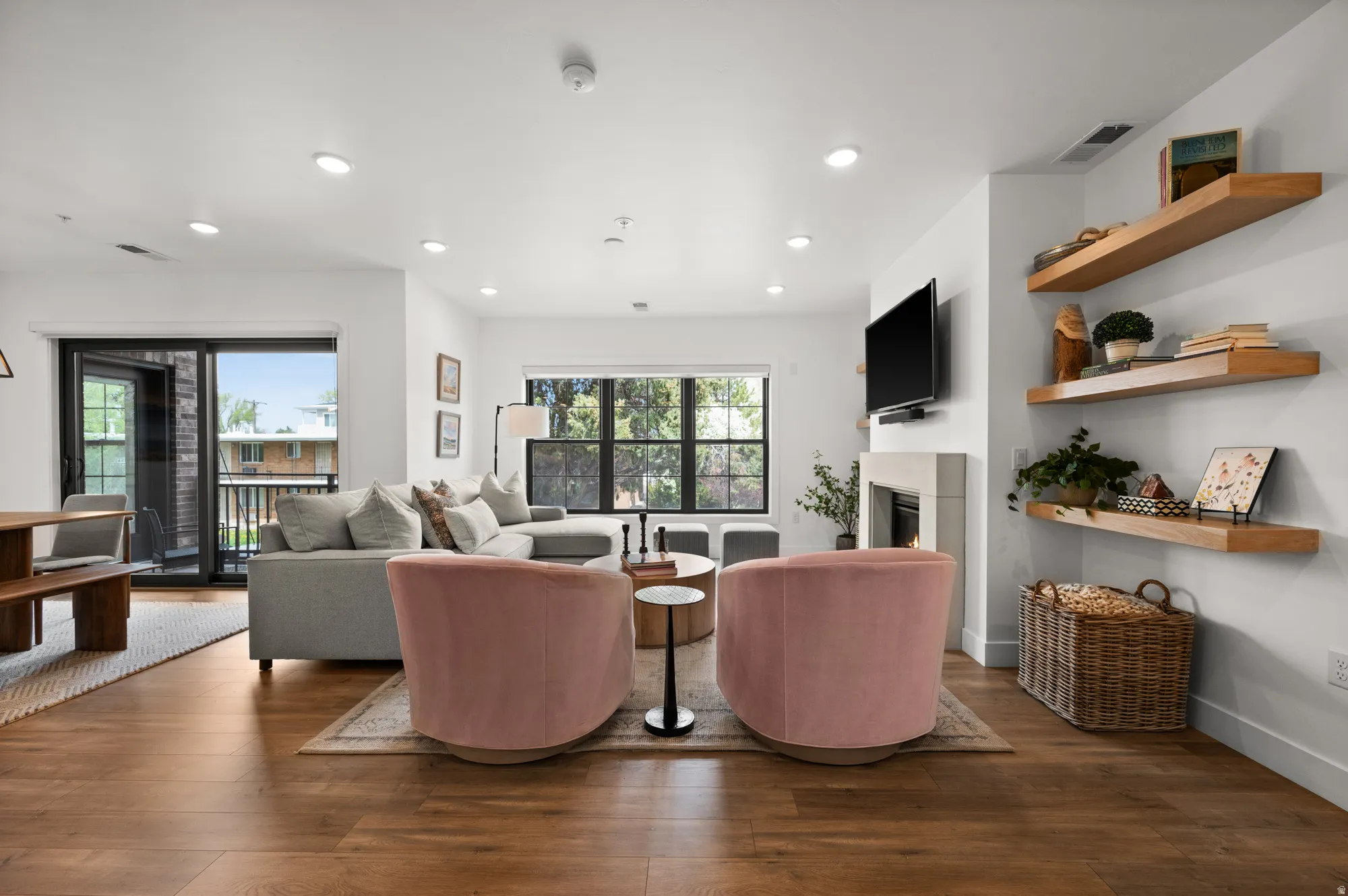 Living room with dark wood finished floors, a glass covered fireplace, and recessed lighting