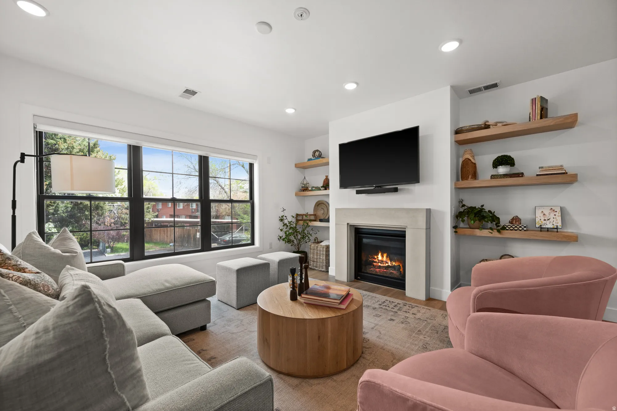 Living room featuring wood finished floors, a glass covered fireplace, and recessed lighting