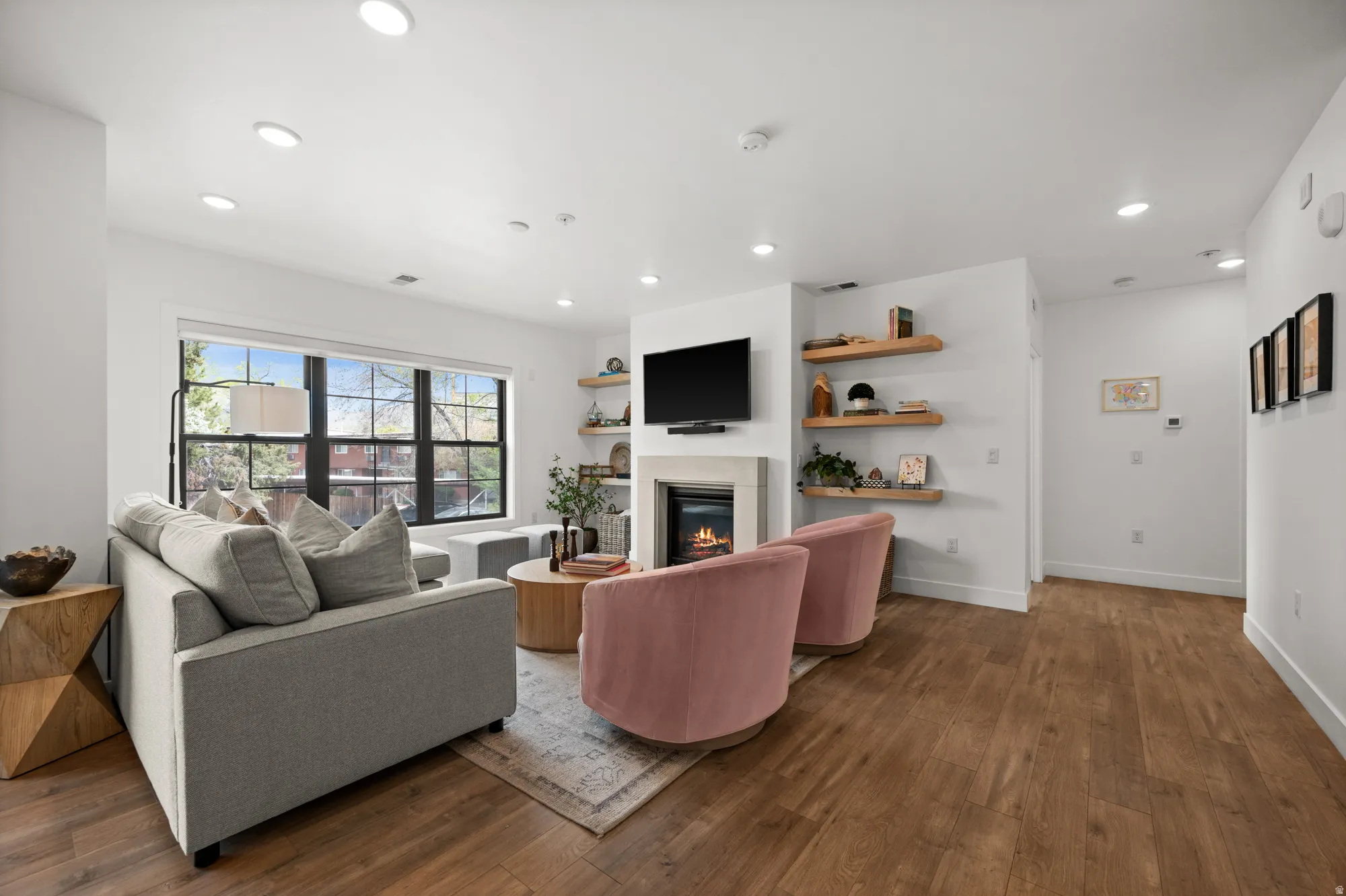 Living area featuring dark wood-style floors, a glass covered fireplace, and recessed lighting