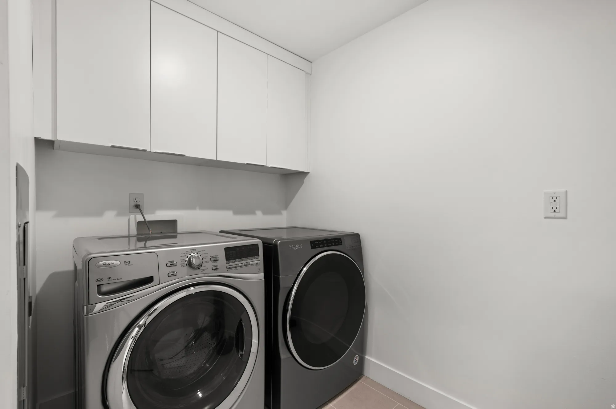 Laundry area featuring cabinet space, washer and dryer, and light tile patterned floors
