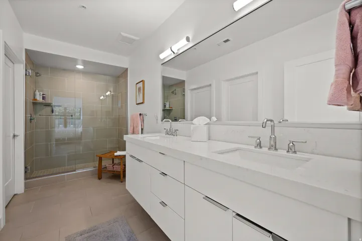 Full bathroom with double vanity, a shower stall, and light tile patterned floors