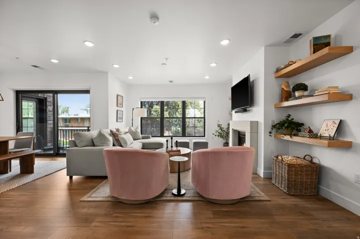 Living room with dark wood finished floors, a glass covered fireplace, and recessed lighting