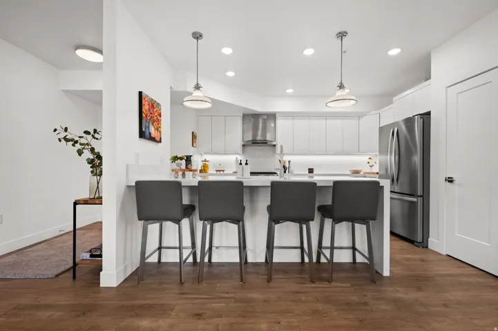 Kitchen featuring a peninsula, a breakfast bar, white cabinetry, and dark wood-style flooring