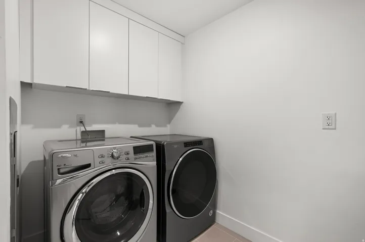 Laundry area featuring cabinet space, washer and dryer, and light tile patterned floors