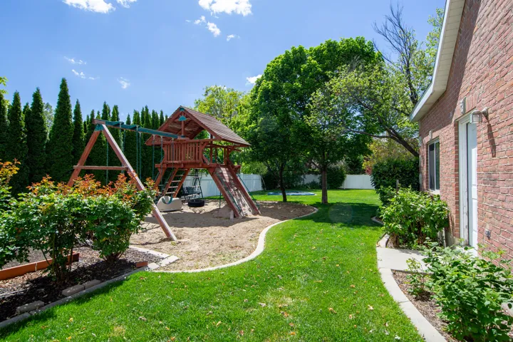 Spacious outdoor area with a wooden play structure, sand pit, and swing set
