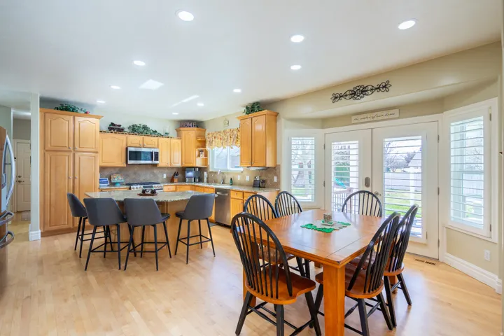 Open-concept kitchen and dining area featuring light wood-finish flooring, recessed lighting, and a kitchen island with seating