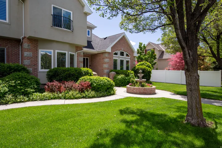 Stately brick and stucco exterior featuring a bay window, decorative Juliet balcony, and a multi-tiered garden fountain
