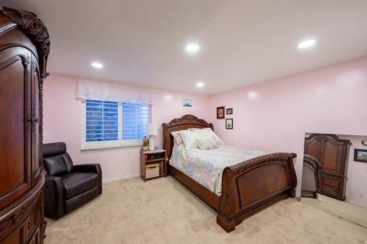 Carpeted room featuring recessed lighting, a window with white plantation shutters, and light pink walls