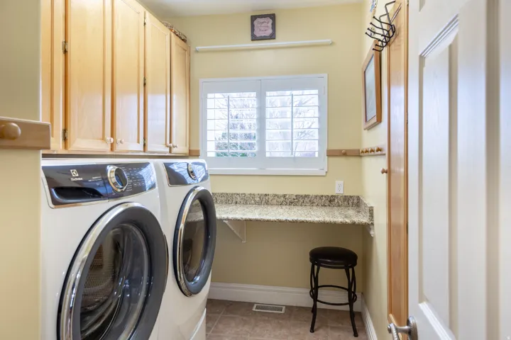 Laundry area featuring upper cabinetry, a mounted countertop, and a window with white louvered shutters